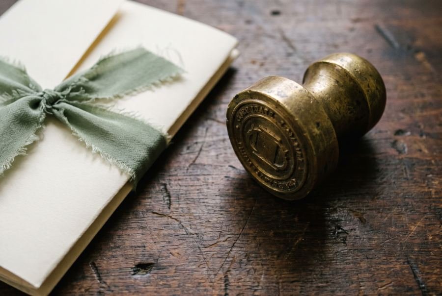 Macro still life of a brass corporate seal stamp and a stock certificate tied with ribbon